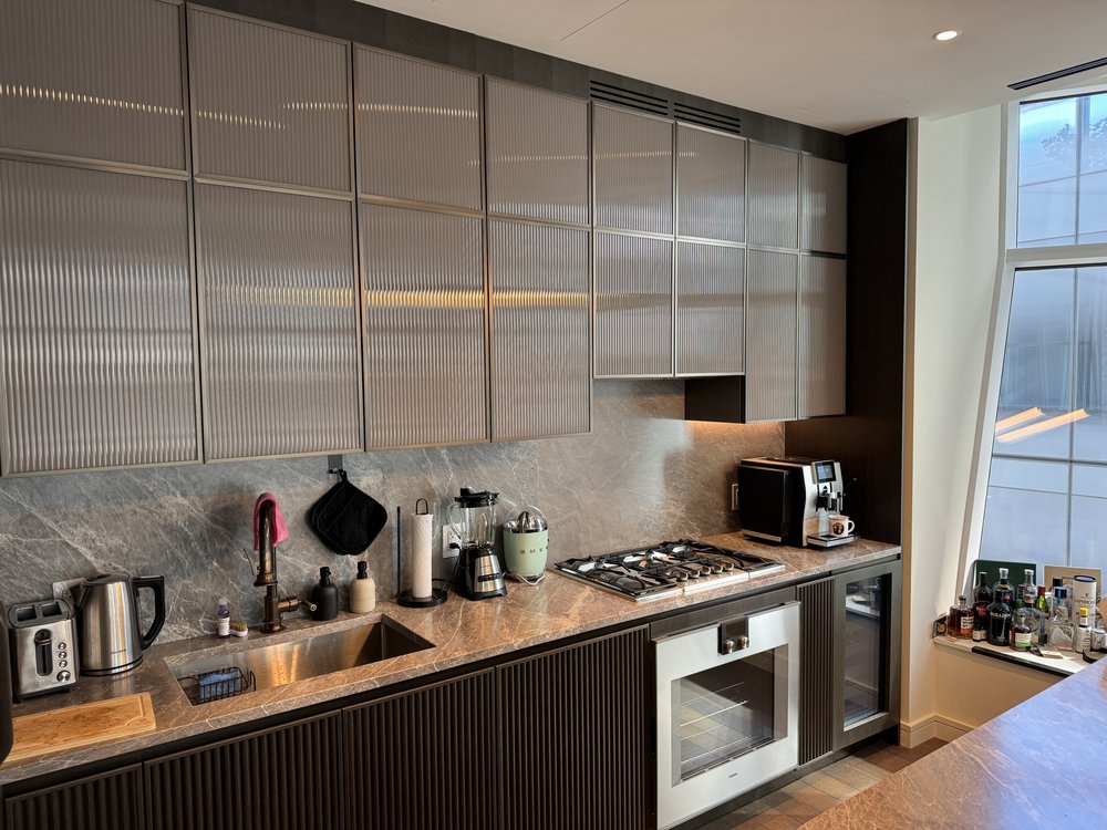 Contemporary kitchen with sophisticated design elements: metallic gray stone or composite backsplash with