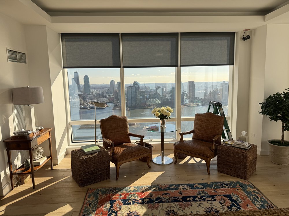 Residential living room with traditional wood furnishings arranged to capture panoramic waterfront and city