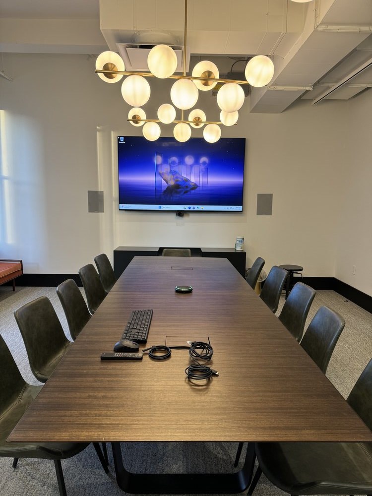 Contemporary conference room featuring a long wooden dining table with modern upholstered chairs in neutral