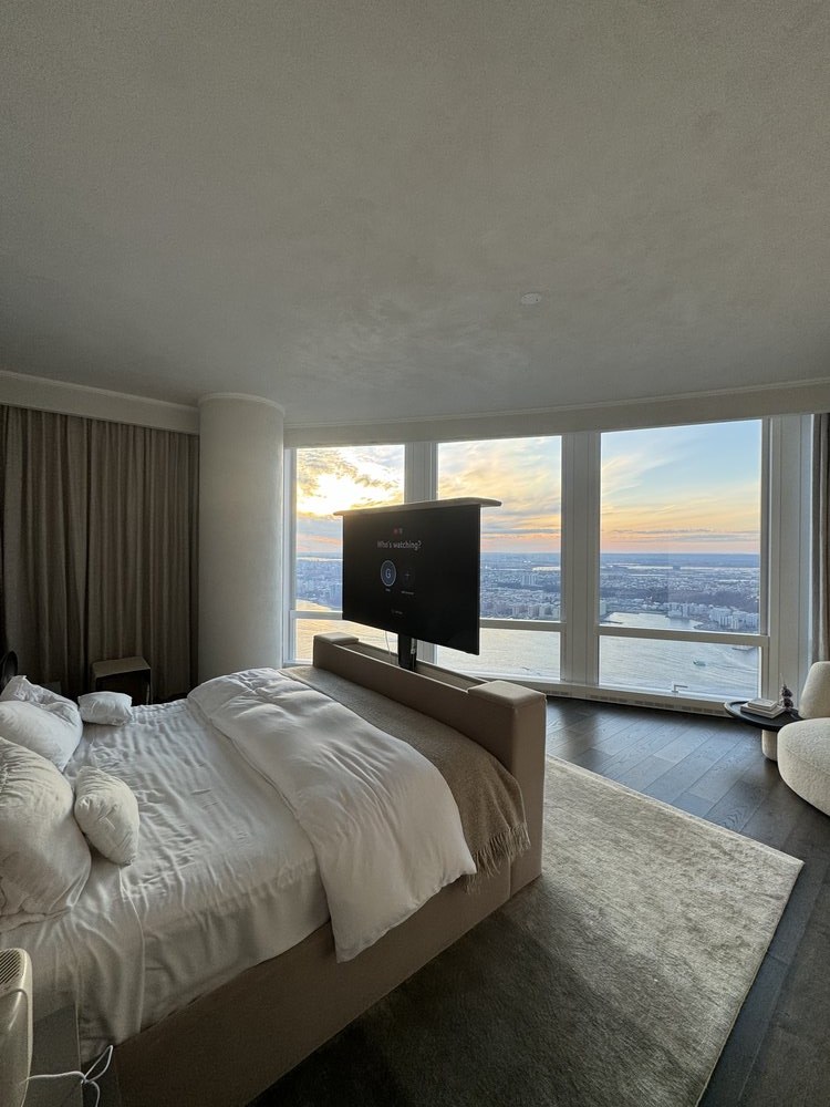 High-rise residential bedroom photographed from the foot of the bed perspective, showcasing a spacious layout