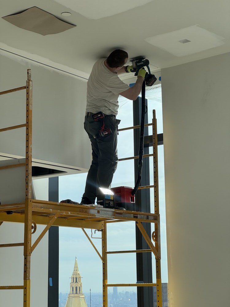 On-site installation photograph showing a technician on a yellow industrial ladder working near a large