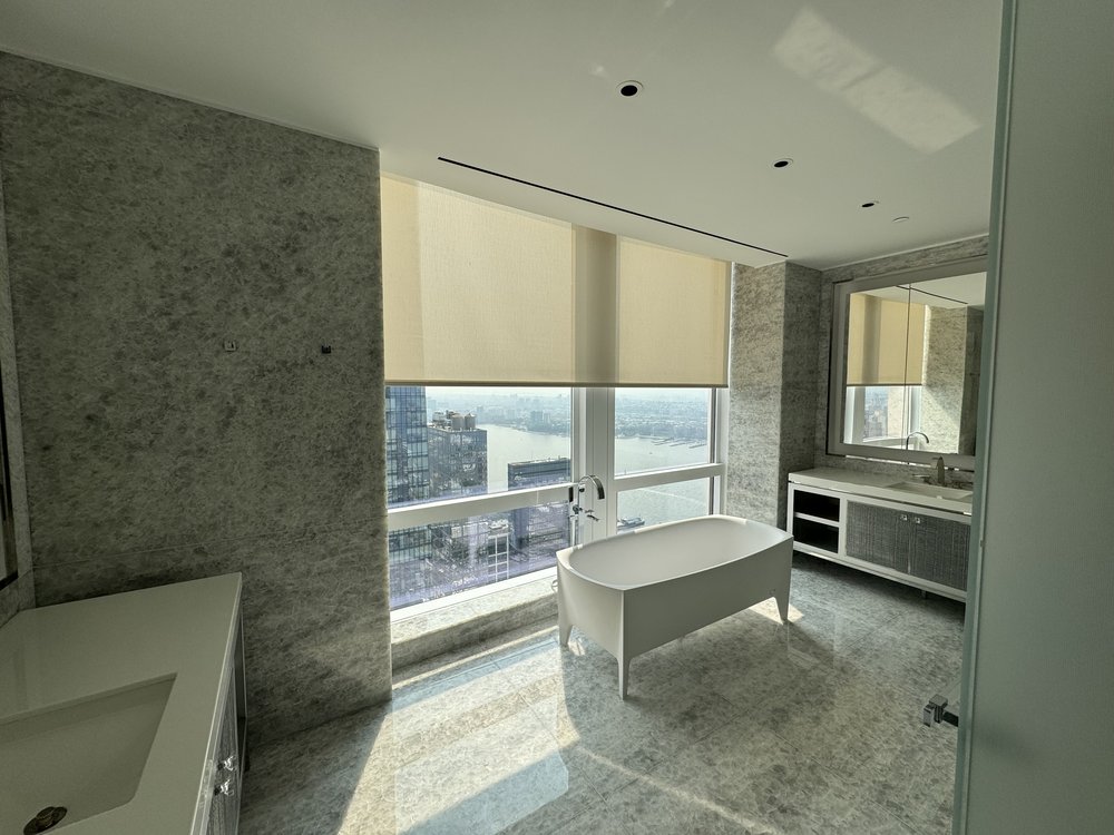 Luxury bathroom featuring freestanding white soaker tub as focal point, marble walls and flooring throughout,