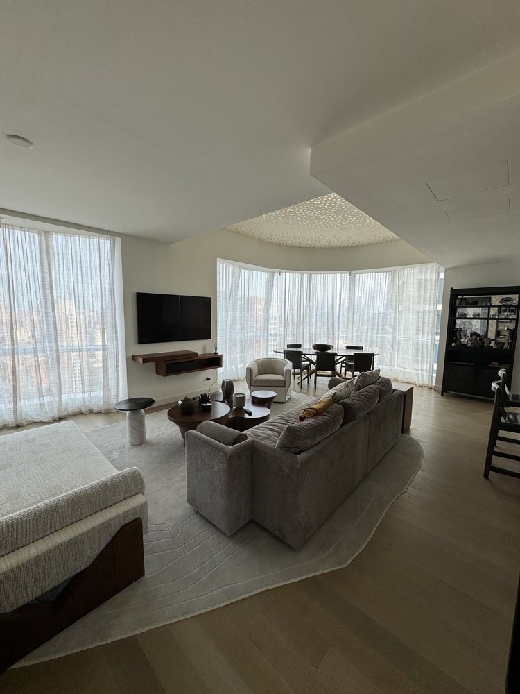 Bedroom or studio space with dark leather accent chair, sheer window treatments providing soft diffused