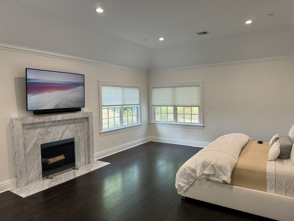 Large media room with sectional tan leather sofa, black upholstered accent armchairs, marble fireplace