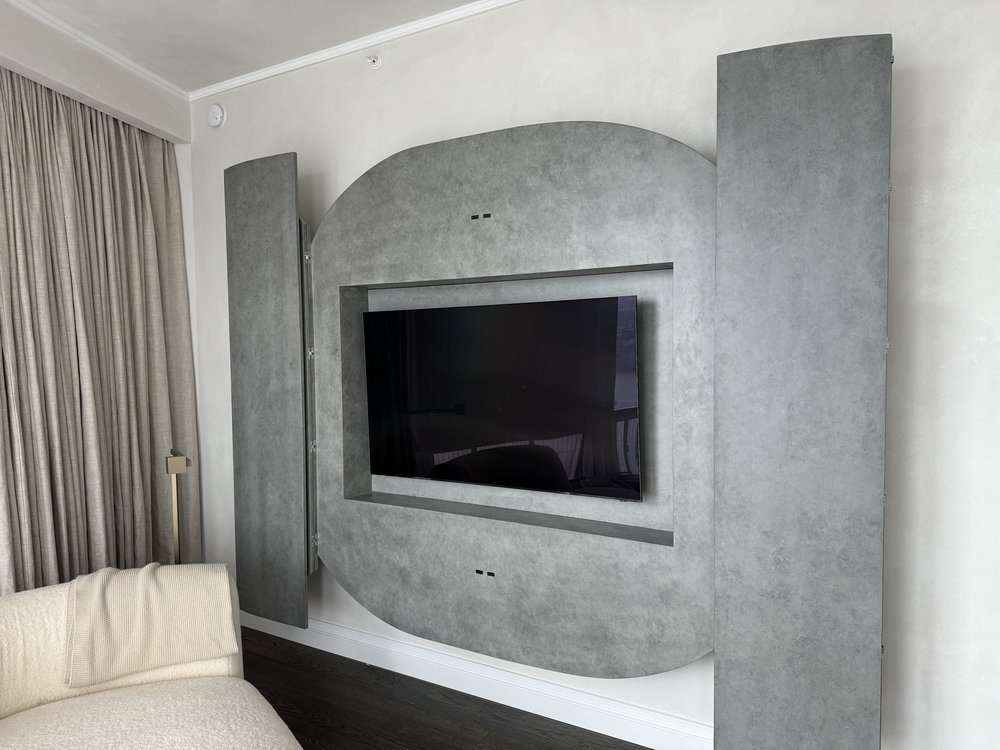 Modern bedroom with distinctive architectural gray concrete or textured accent wall featuring curved