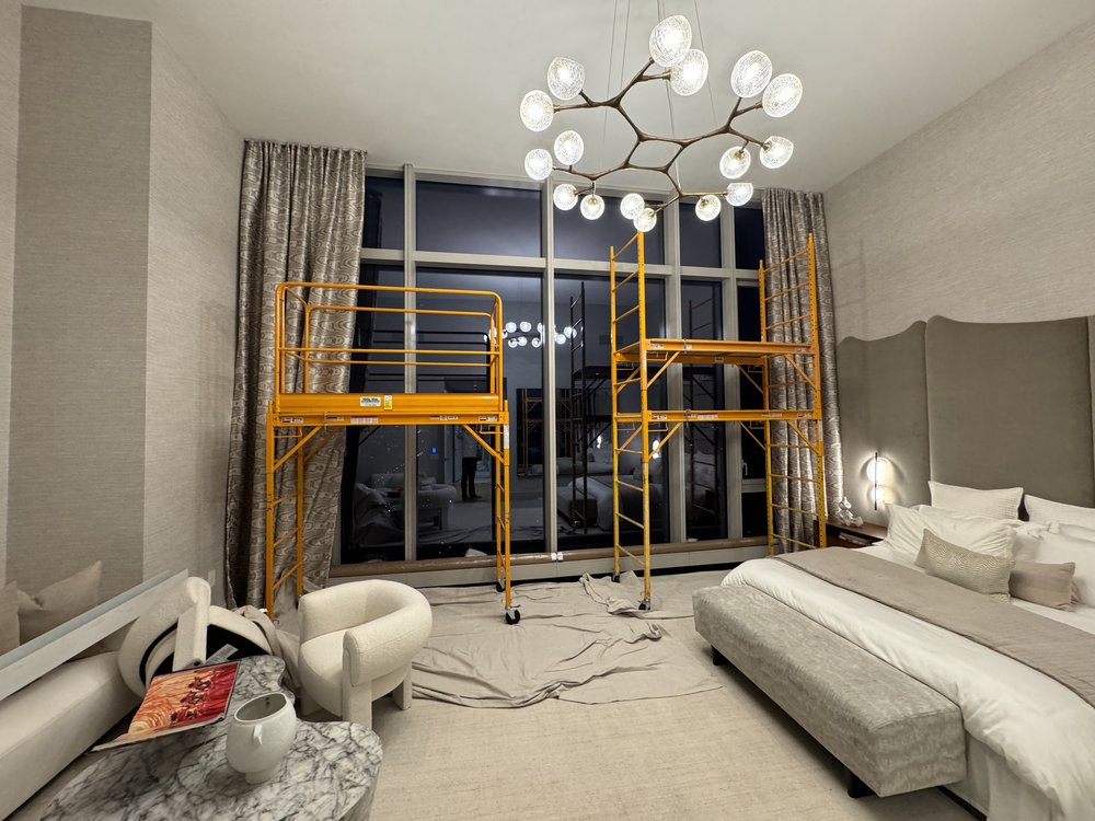 Luxury master bedroom during renovation phase featuring dramatic artistic branch-form lighting fixture with